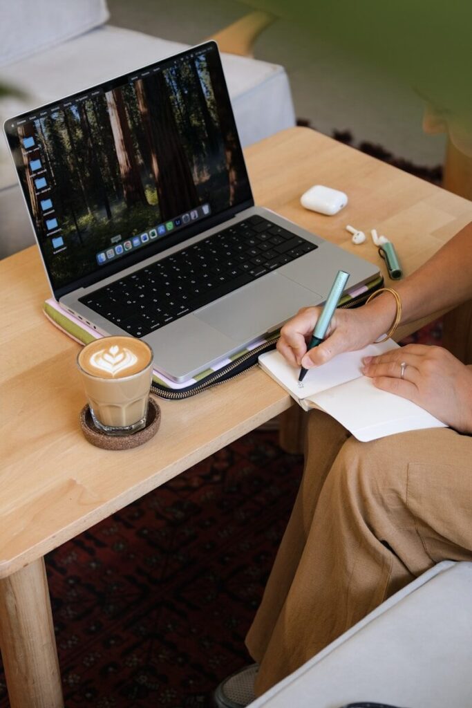 Uma mesa de madeira com um caderno aberto, uma caneta e uma xícara de café ao lado de um livro, representando o conforto e a clareza mental no lar.